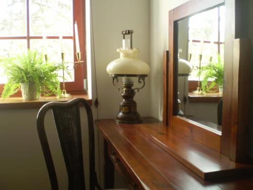a lamp sitting on a wooden table next to a mirror at Penzion Rozmarýn in Vsetín