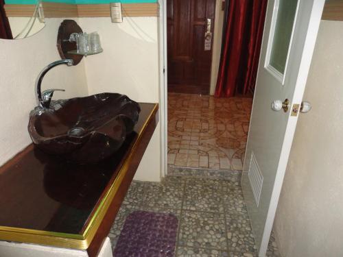 a bathroom with a black sink and a hallway at Deep Forest Garden Hotel in Puerto Princesa City