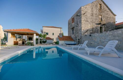 una piscina con due sedie e una casa di Seaside Villa Mia Trogir a Trogir