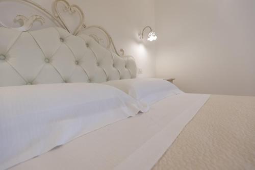 a white bed with a white headboard and white pillows at Dimora San Quirico - bed e breakfast - Cisternino in Cisternino