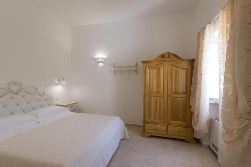 a bedroom with a white bed and a wooden cabinet at Dimora San Quirico - bed e breakfast - Cisternino in Cisternino