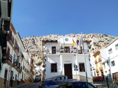 a building with cars parked in front of a mountain at Casa Clara, Caminito de Rey in Valle de Abdalagís