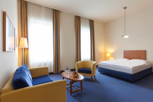 a hotel room with a bed and a couch and a table at Vienna House by Wyndham Baltic Stralsund in Stralsund