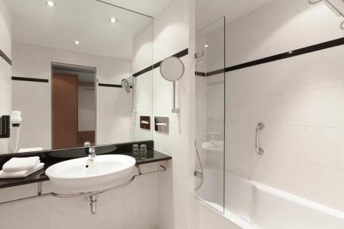 a white bathroom with a sink and a shower at Vienna House by Wyndham Baltic Stralsund in Stralsund