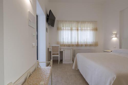a white bedroom with a bed and a desk at Dimora San Quirico - bed e breakfast - Cisternino in Cisternino