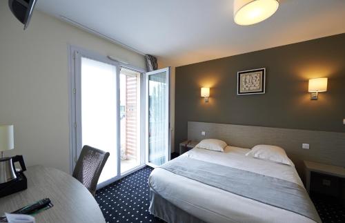 a hotel room with a bed and a window at Park Hôtel & Appartements in Cholet