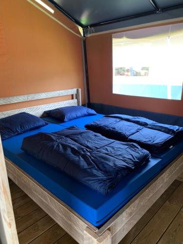 un letto in una camera con lenzuola e cuscini blu di Easyatent FKK Safari tent Ulika Naturist - clothes free a Poreč (Parenzo)