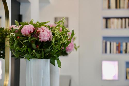 a white vase filled with pink flowers in a room at Stella Etoile in Paris