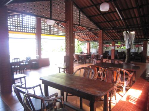 Un restaurante con mesas y sillas de madera en una sala. en Pine Bungalow Krabi, en Klong Muang Beach