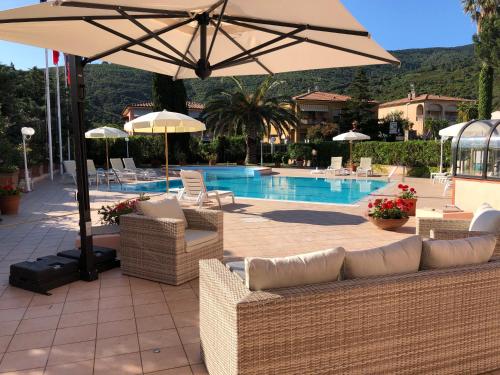 a patio with chairs and an umbrella next to a pool at Arthotel Gabbiano Azzurro Due in Marciana Marina