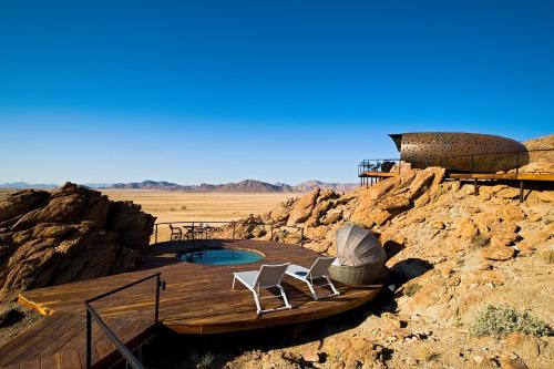 a deck with chairs and a pool in the desert at Desert Whisper in Solitaire