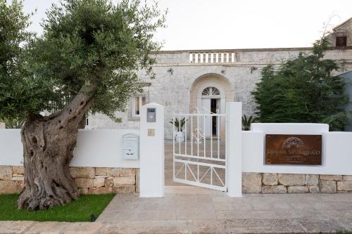 a white gate with a tree in front of a building at Dimora San Quirico - bed e breakfast - Cisternino in Cisternino