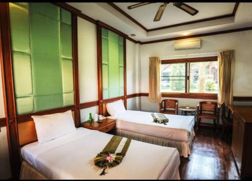 a hotel room with two beds and a window at Suan Bua Hotel & Resort in Ban Pong