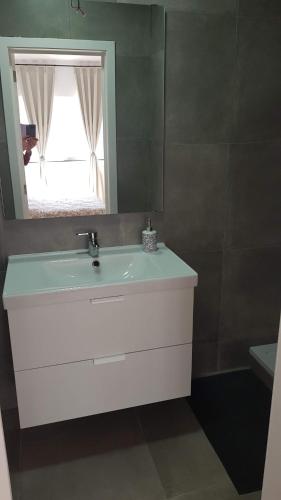een badkamer met een witte wastafel en een spiegel bij Attractive modern apartment in Brussel