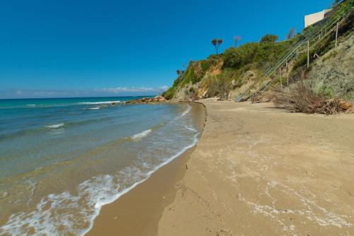 a sandy beach with the ocean on a sunny day at Villa Angela in Ágios Matthaíos