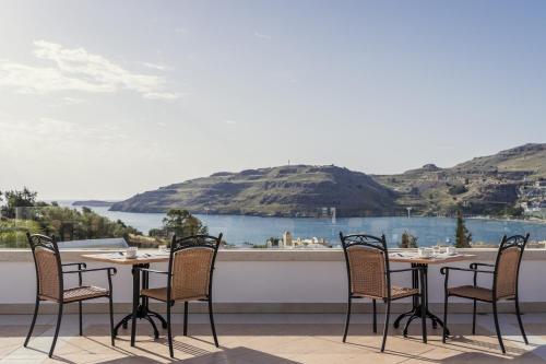 a table and chairs on a balcony with a view of the water at Lindos Village Resort & Spa - Adults Only in Líndos
