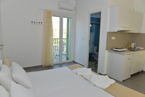 a white bedroom with a large bed and a kitchen at Zeras Apartments in Adamas