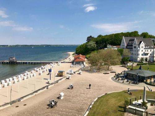 a beach with white umbrellas and people on it at Appartement FoerdeHimmel in Glücksburg