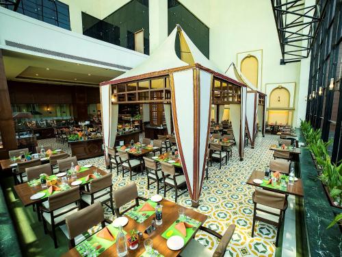 a restaurant with tables and chairs in a building at The Orchid Hotel Hinjewadi Pune in Pune