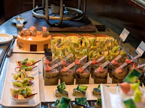 a buffet of food with fruit and desserts on a table at The Orchid Hotel Hinjewadi Pune in Pune