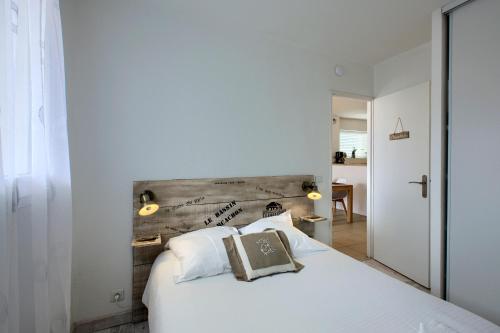 アンデルノ・レ・バンにあるAppt. Bella Vita - Andernos les Bains, au cœur du Bassin d'Arcachonの白いベッド1台(木製ヘッドボード付)が備わるベッドルーム1室が備わります。