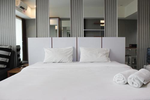 a bedroom with a white bed with towels on it at Bright Studio @ Tamansari La Grande Apartment By Travelio in Bandung