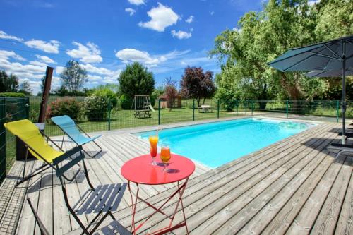 a deck with a table and chairs next to a swimming pool at Kyriad Libourne Saint Emilion in Arveyres