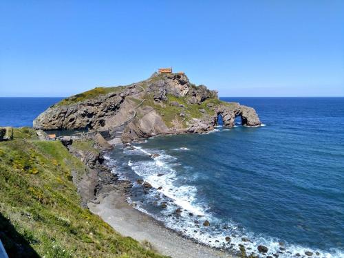 a small island in the ocean with a house on it at Laga Blue Surf in Ibarrangelu