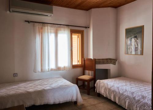une chambre avec deux lits et une fenêtre et une chaise dans l'établissement Estate with amazing views of Poros, à Poros