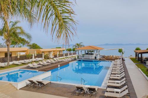 a beach area with a pool, chairs, and a beach umbrella at Villa Di Mare Seaside Suites in Ixia