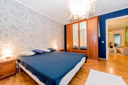 a bedroom with a blue bed and a chandelier at Cozy beach apartment in Pärnu