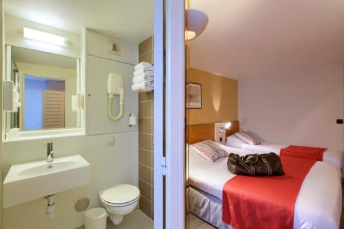 La salle de bains est pourvue de 2 lits, d'un lavabo et de toilettes. dans l'établissement Kyriad Libourne Saint Emilion, à Arveyres