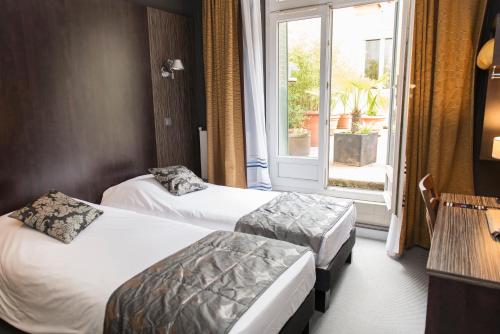 a hotel room with two beds and a window at Hôtel Astoria in Nantes