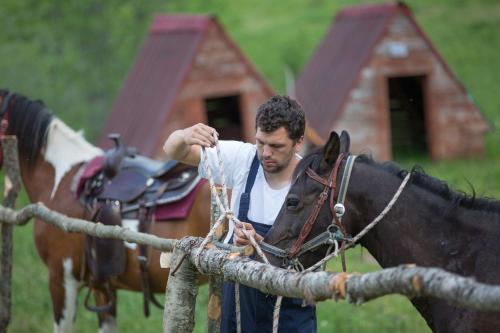 Um homem está ao lado de um cavalo. em Etno Village Vojnik em Šavnik