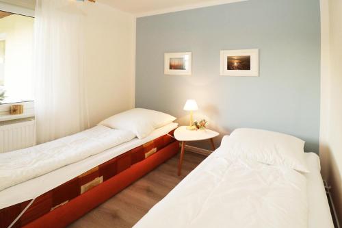 een kamer met 2 bedden, een tafel en een raam bij Heydens Ferienhaus_HEYD in Ostseebad Karlshagen