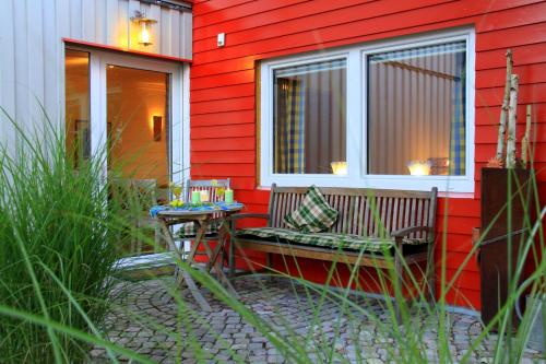 a bench sitting outside of a red house with a table at Ana's Landhaus auch für Monteure in Heretsried