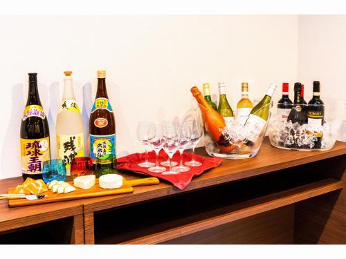 a wooden table with bottles and glasses of wine at Yenns Marina Inn Mercy in Ginowan