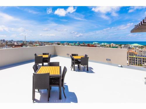 a balcony with tables and chairs on a roof at Yenns Marina Inn Mercy in Ginowan