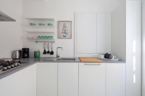 a white kitchen with white cabinets and a sink at "Vicolo Apartment" is a Two-story Apartment, 2BDR, additional Sofabed, 2,5 BTH, Aircondo, Pedestrian Centre, Private Parking 600mt far, easy to train and ferries, city life in La Spezia
