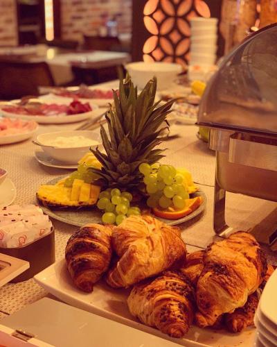 Una mesa con croissants y uvas y otros alimentos. en Carpe Diem Boutique Hotel, en Zenica
