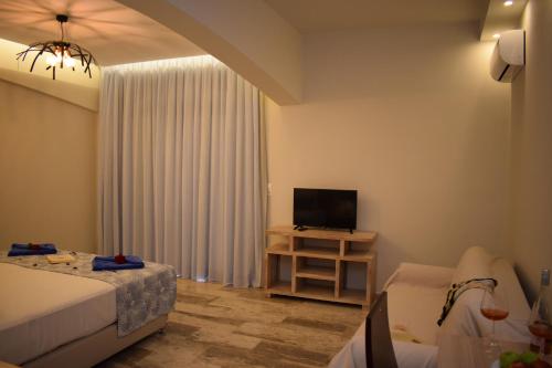 1 dormitorio con 1 cama y mesa con TV en Myrtis Spa Hotel en Plakias