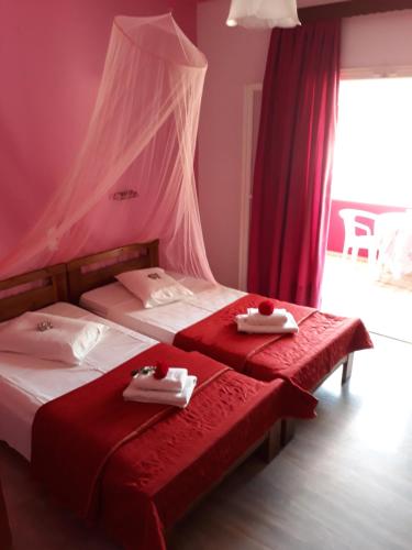 two twin beds in a room with red curtains at MARGARITAS' ROOMS in Agios Gordios