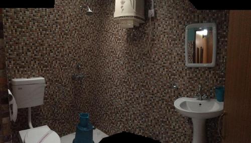 La salle de bains est pourvue d'un lavabo, de toilettes et d'un miroir. dans l'établissement Vamoose Dolma, à Tawang