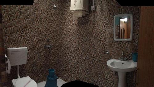 a bathroom with a sink and a toilet and a mirror at Dolma in Tawang