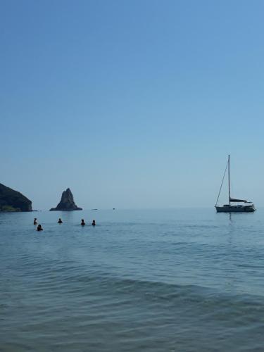 a group of people swimming in the water with a sailboat at MARGARITAS' ROOMS in Agios Gordios