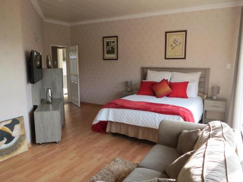 a bedroom with a bed with red pillows and a couch at Mountain Beauty in Mbabane