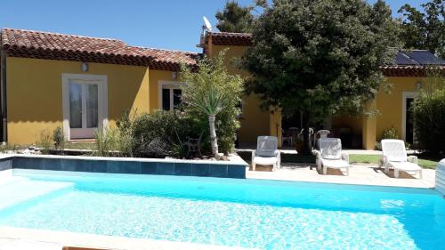 - une piscine en face d'une maison avec 2 chaises dans l'établissement La Villa Provençale, à Lorgues