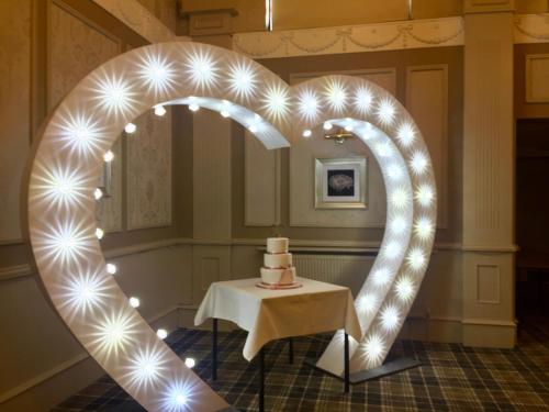 a heart shaped arch with a cake on a table at The Corner House Hotel in Annan