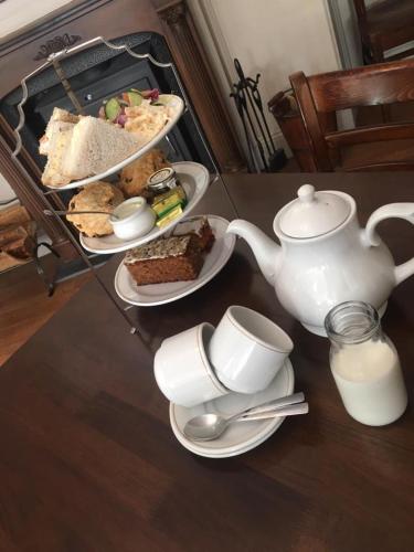 a table with plates of food and a tea kettle at The Corner House Hotel in Annan