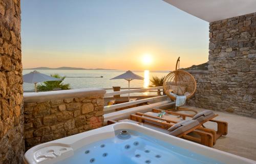 a jacuzzi tub on a patio with the ocean at Anax Resort and Spa in Agios Ioannis Mykonos
